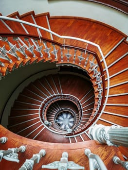 Top down look to Old spiral staircase with ornaments in tenement house 