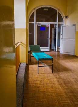 Hospital bed in corridor near staircase in old abandoned hospital