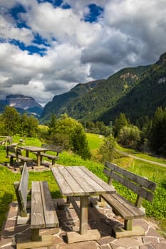 Nature landscape. Amazing view on Alps, valley and mountains at summer. It's time for lunch in the mountains. Picnic table in Dolomites mountains, wooden bench in the mountain valley.