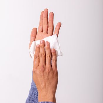 Young man cleaning hands with wet wipes