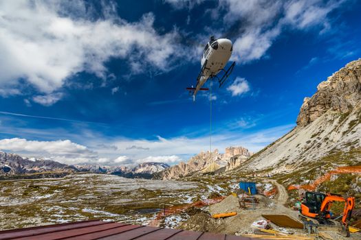 Helicopter used for rescue operations also for bringing construction materials, on the ground Tre Cime di Lavaredo in Dolomites, Italy. 