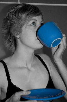 Woman in monochrome drinking from blue cup