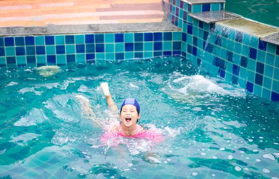 little asian girl wearing inflatable sleeves playing in the pool