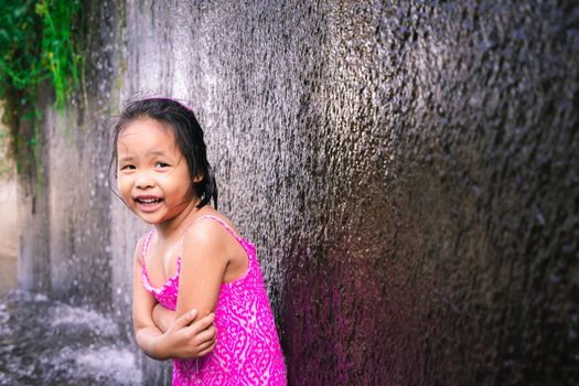 happy little asian girl feeling cold while playing water in spillway of weir