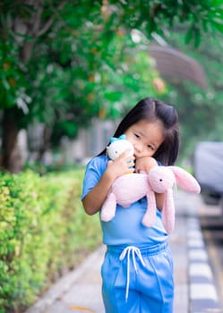 Cute little asian girl with a doll in the park