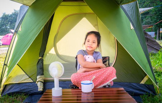 little girl sitting in tent while going camping.The concept of outdoor activities and adventures in nature.