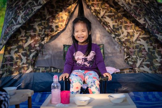 little girl sitting on the chair while going camping.The concept of outdoor activities and adventures in nature.