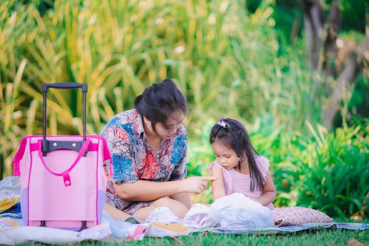 mother put on cream to duughter's arm during a picnic in the park