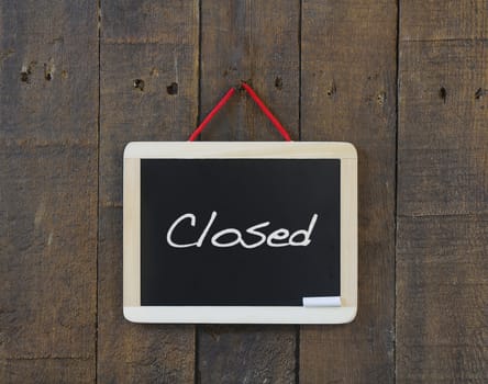 Blackboard hanging on a old wooden wall with closed word.