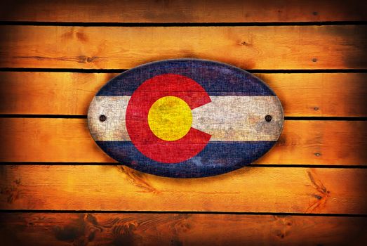 A Colorado flag on brown wooden planks.