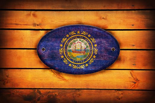 A New Hampshire flag on brown wooden planks.