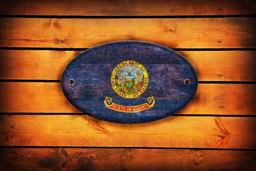 A Idaho flag on brown wooden planks.