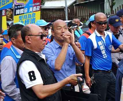 KAOHSIUNG, TAIWAN -- NOVEMBER 10, 2018: KMT Kaohsiung mayor candidate Han Guo-Yun (center, blue shirt), surrounded by security, greets supporters on his arrival at an election rally.
