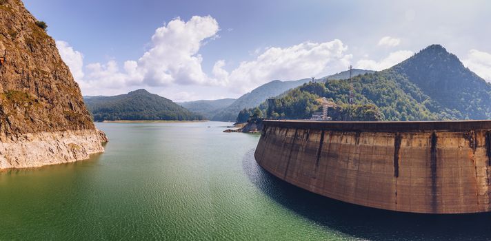 Summer scenery of Vidraru Dam and lake glowing in sunlight. Vidraru Dam, Romania. Carpathian Mountains, Fagaras ridge.