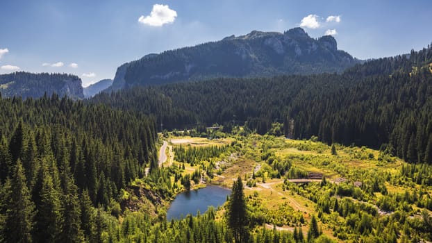 View to Bolboci lake from the damb with carpathian mountains at the background, Sinaia, Romania.