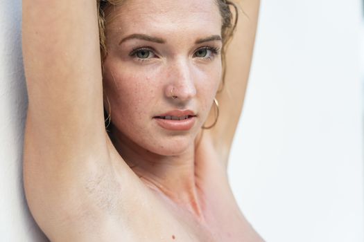 A beautiful blonde topless model against a white wall in the Yucatán Peninsula near Merida, Mexico