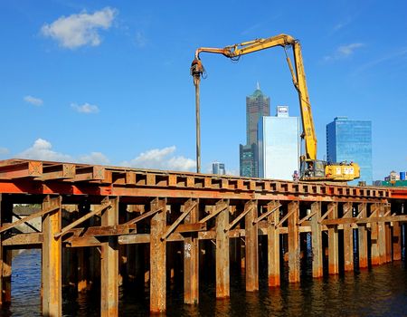 KAOHSIUNG, TAIWAN -- JUNE 14, 2015: An excavator drives a pile into the river bed as construction of a new bridge across the Love River continues.