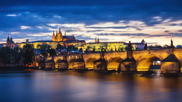 Prague Castle and the Charles Bridge at sunset in Prague, Czech Republic, Vltava river in foreground