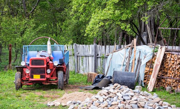 Rural scene of a backyard with tractor and wood pile