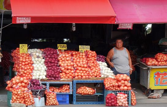 PINGTUNG, TAIWAN -- JULY 6 , 2017: At a market for agricultural products vendors offer large sacks of onions, a local specialty.