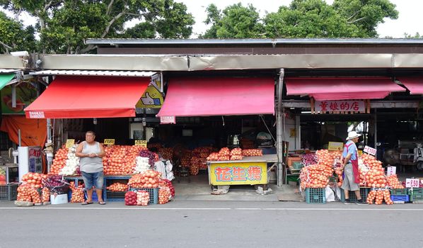 PINGTUNG, TAIWAN -- JULY 6 , 2017: At a market for agricultural products vendors offer large sacks of onions, a local specialty.