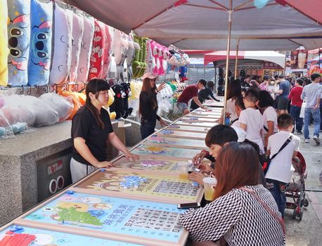 KAOHSIUNG, TAIWAN -- FEBRUARY 6, 2019: People play Bingo at an outdoor market hoping to win prizes such as stuffed animals and cartoon merchandise.
