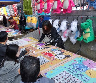 KAOHSIUNG, TAIWAN -- FEBRUARY 6, 2019: People play Bingo at an outdoor market hoping to win prizes such as stuffed animals and cartoon merchandise.