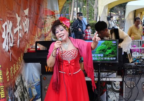 KAOHSIUNG, TAIWAN -- FEBRUARY 9, 2019: A female performer sings Karaoke songs on the banks of the Love River during the Lantern Festival.