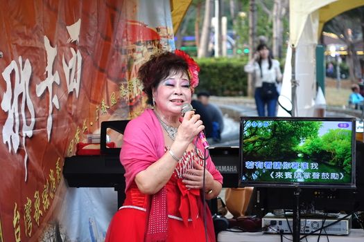 KAOHSIUNG, TAIWAN -- FEBRUARY 9, 2019: A female performer sings Karaoke songs on the banks of the Love River during the Lantern Festival.