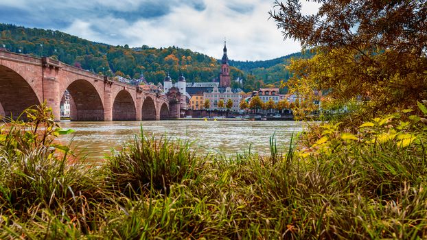 View on Heidelberg in autumn with red foliage including Carl Theodor Old Bridge, Neckar river, Church of the Holy Spirit, Germany