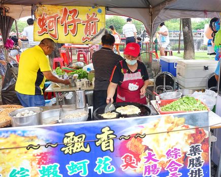 KAOHSIUNG, TAIWAN -- JUNE 9, 2016: An outdoor food stall prepares oyster omelets, a popular Taiwanese street food.