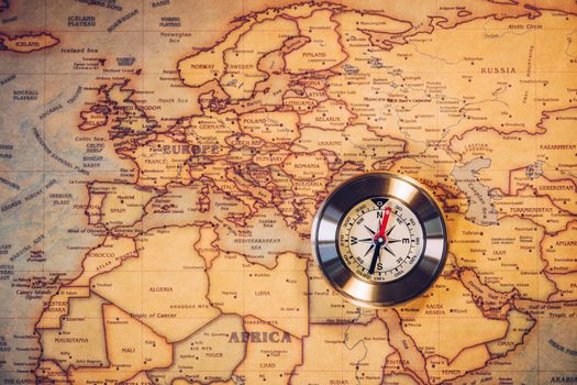 Old vintage retro golden compass on ancient map. Selective focus, shallow depth of field. Concept of world travel, sightseeing and tourism.