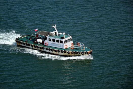 KAOHSIUNG, TAIWAN -- SEPTEMBER 12 , 2017: A small pilot boat returns to port after guiding a large vessel into the harbor.