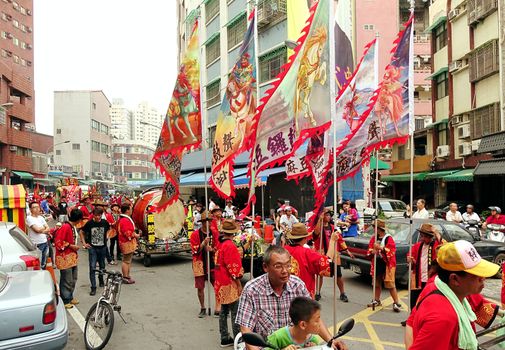 KAOHSIUNG, TAIWAN -- APRIL 20, 2014: A religious procession with flags and drums makes its way through a narrow street.