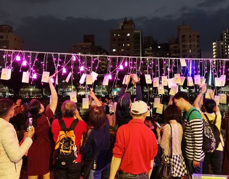 KAOHSIUNG, TAIWAN -- FEBRUARY 9, 2019: People hang up wish cards during the 2019 Lantern Festival on the banks of the Love River.