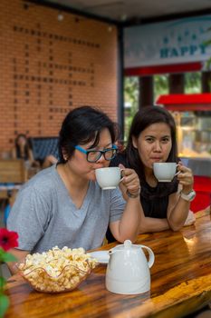 Best friends beautiful asian women drinking coffee and tea with popcorn have a friendship in talking and chatting in cafe coffee shop