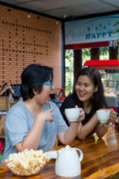 Frosted glass filter blurred of Best friends beautiful asian women drinking coffee and tea with popcorn have a friendship in talking and chatting in cafe coffee shop