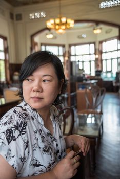 Asian women 40s white skin in white and black dress have a lovely turn face gesture wait for something in a coffee shop cafe vintage style