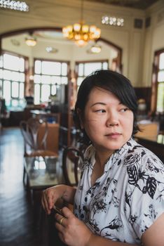 Asian women 40s white skin in white and black dress have a lovely turn face gesture wait for something in a coffee shop cafe vintage style