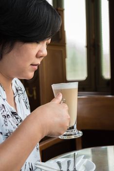 Asian women 40s white skin in white and black dress have a lovely drinking a hot coffee gesture wait for something in a coffee shop cafe vintage style