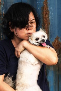 Asia women and dog happy smile hugging her pat is a dog so cute mixed breed with Shih-Tzu, Pomeranian and Poodle with rusty blue industry container background