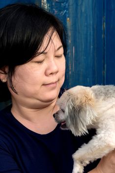 Asia women and dog happy smile hugging her pat is a dog so cute mixed breed with Shih-Tzu, Pomeranian and Poodle with rusty blue industry container background