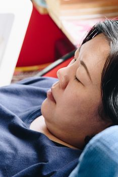 Asian women 40s white skin and plump body in blue t-shirt have a doubt and think gesture on a blue sofa near window