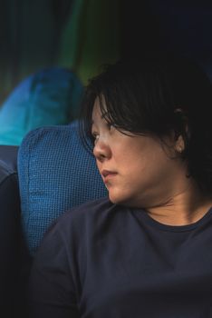 Asian women 40s white skin and plump body in blue dress have a doubt and think gesture on a blue sofa near window