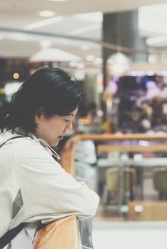 Asian women 40s white skin plump body with backpack and jacket waiting in department store or shopping mall