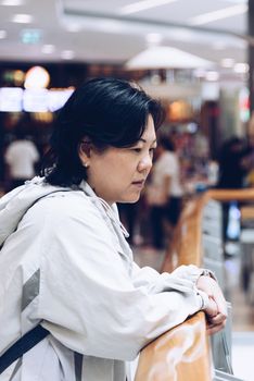 Asian women 40s white skin plump body with backpack and jacket waiting in department store or shopping mall