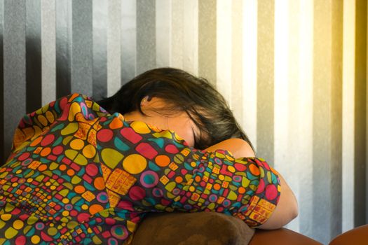 Asia woman plump body take a nap or sleep on a brown sofa Because fatigue or tired , process in soft orange sun light style