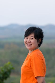 Asia woman plump body in orange T-shirt posing and smile at mountain view when travel