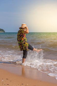 Asia woman plump body in colorful dress with hat posing at beach with blue sea and sky when travel , process in soft orange sun light style