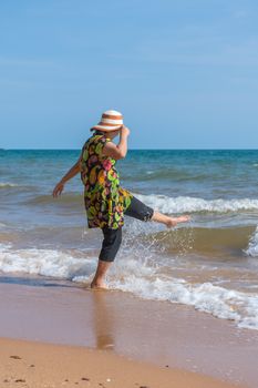 Asia woman plump body in colorful dress with hat posing at beach with blue sea and sky when travel